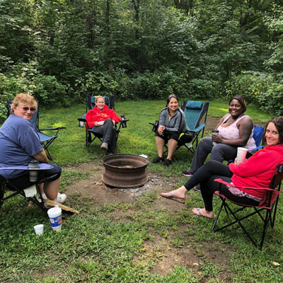 Diverse women sitting around a fire pit at a Deep Water retreat