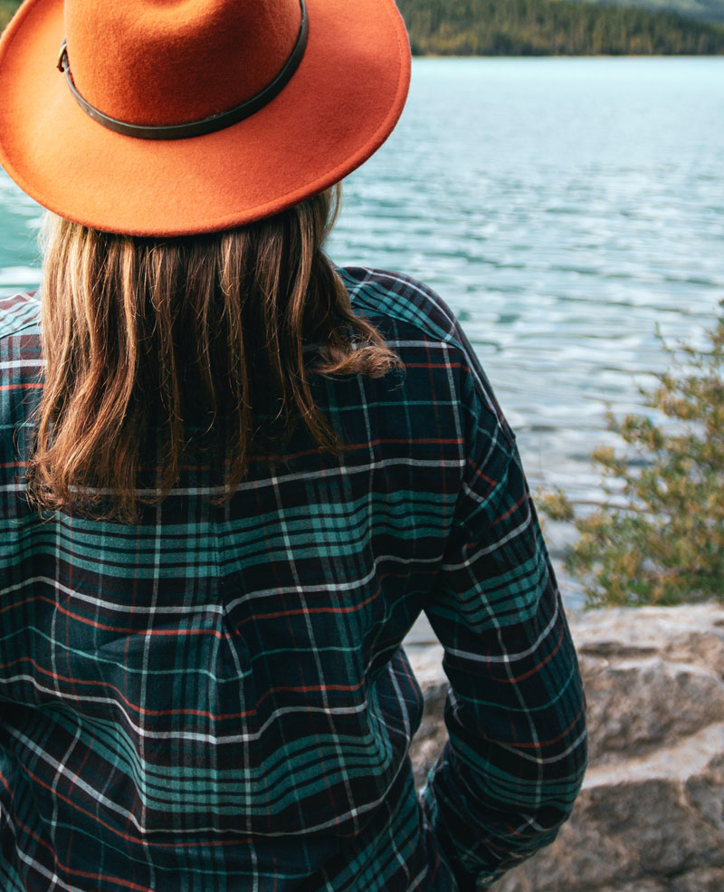 Woman with hat looking at a lake's horizon