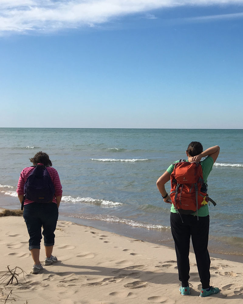 A fall day retreat at Nordic Dunes on Lake Michigan, two women hiking along the water's edge